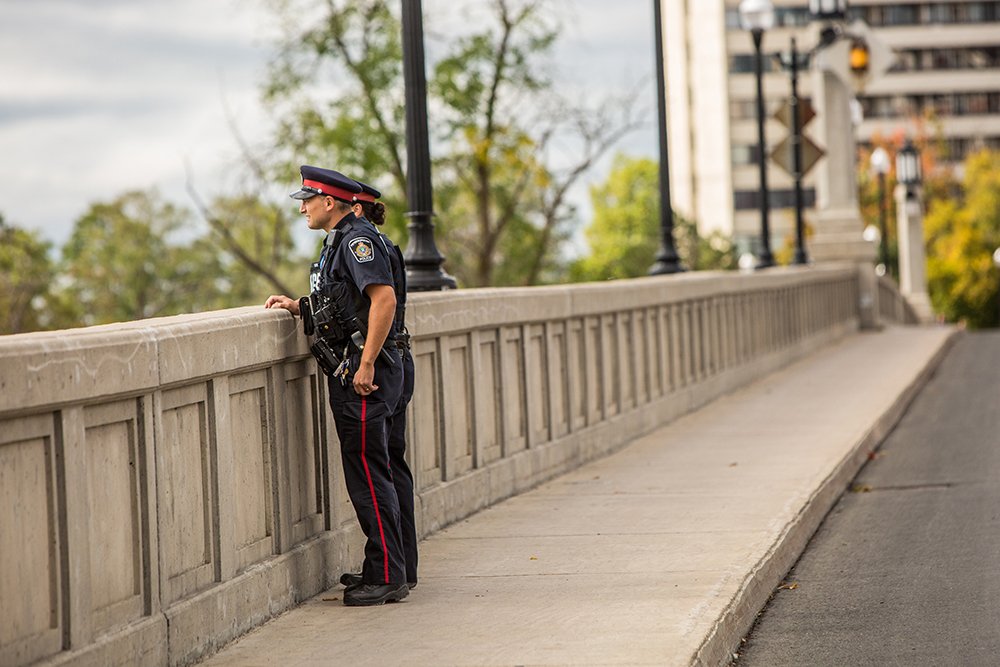 2 Peterborough Police Officers look over the side of a large concrete bridge