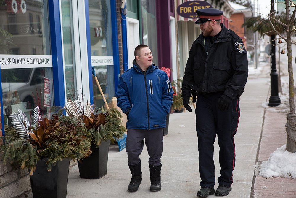 A Peterborough Police officer walks down the street with a citizen while having a lighthearted conversation