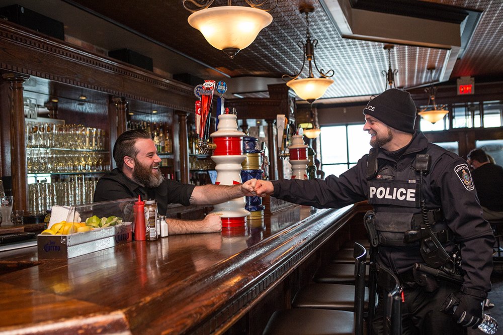 A Peterborough POlice officer fist bumps a bartender across the pub bar