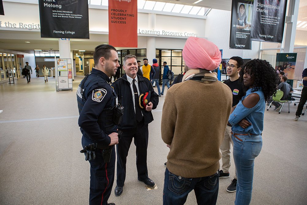 2 Peterborough Police officers engaged in casual conversation with citizens at Fleming College