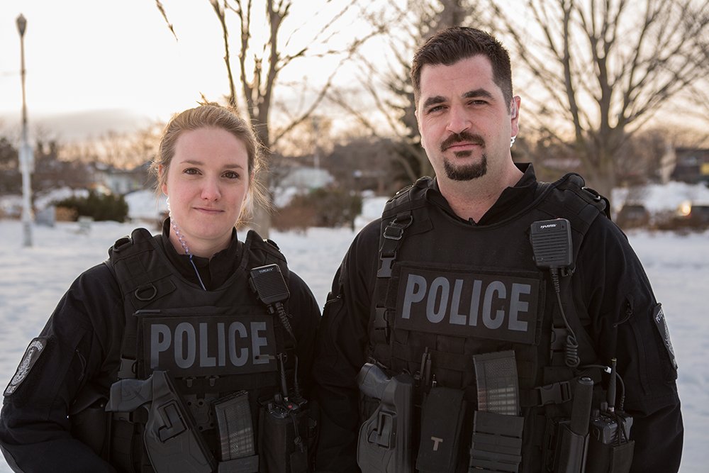 2 police officers stands side by side smiling for a picture in winter