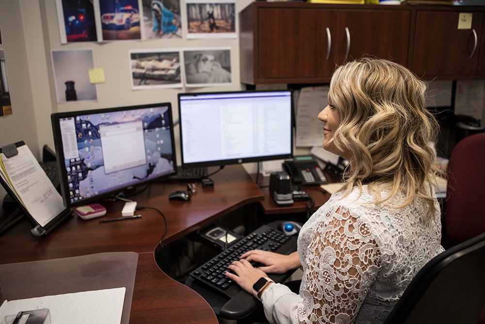 A city clerk sits behind a desk typing an email 