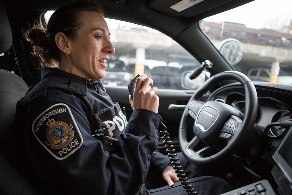 A Peterborough Police officer speaks into her radio in the front seat of a patrol car
