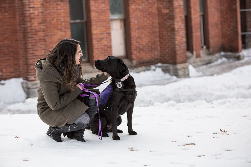 A victim services coordinator squats down to pet the facility dog