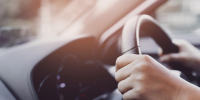 Person with hands on steering wheel of car