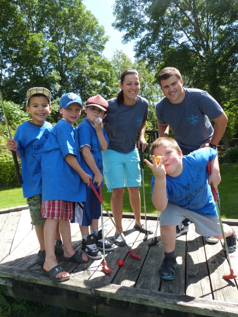 2 Police officers in plain clothes pose with kids at a mini golf course