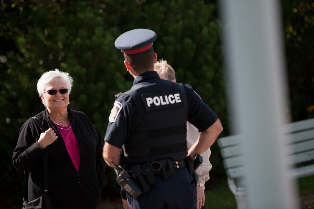 A police officers has a lighthearted conversations with 2 seniors in a park