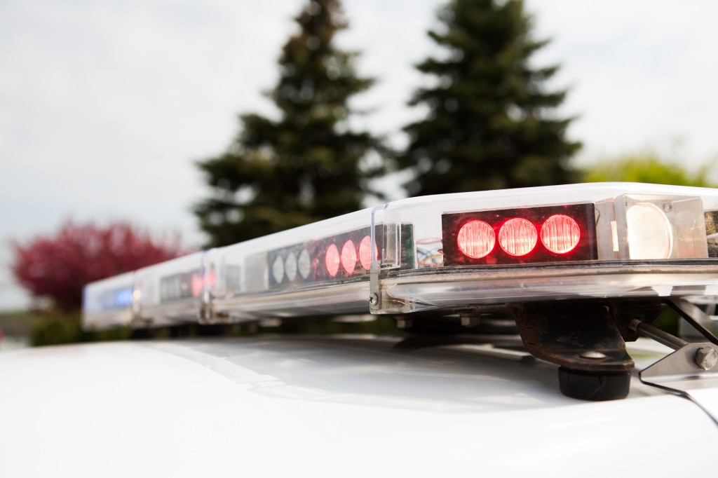 Image shows the top of a police car with the lights flashing 