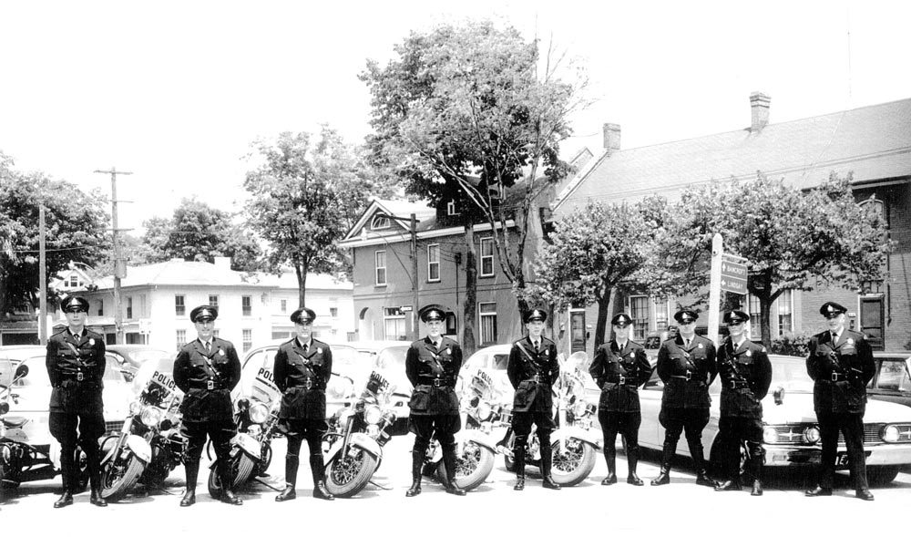 Historic black and white group photograph of Peterborough Police Service Officers standing in front of their motorcycles.